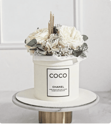 a chanel perfume bottle with flowers in a white box