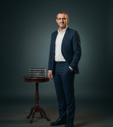 Hombre con traje de pie frente a una mesa con libros