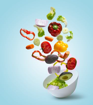 a bowl of vegetables being tossed in a bowl