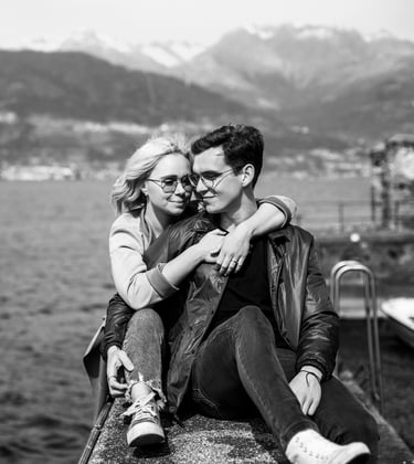 a man and woman sitting on a ledge overlooking the water