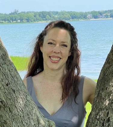 a woman in a dress standing in front of a tree