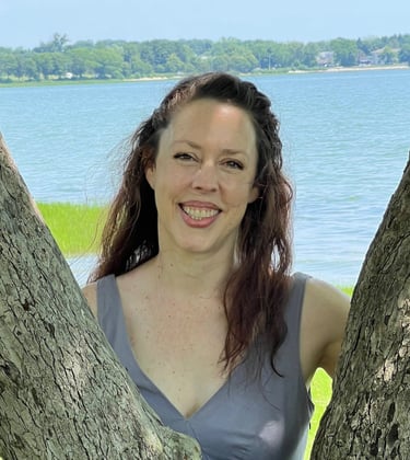 a woman in a dress standing in front of a tree