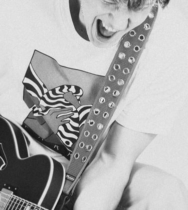 portrait of a man jumping in a white shirt and tie dye on a guitar