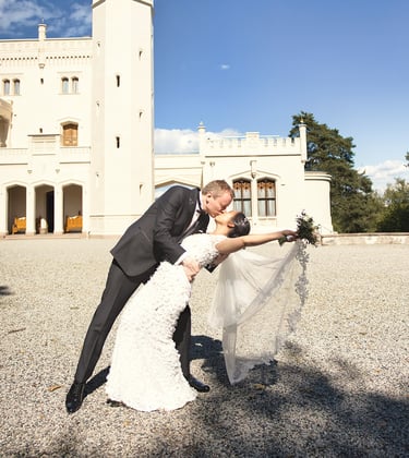 a bride and groom kissing in front of a castle