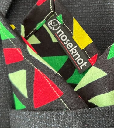 A Noseknot handkerchief showing the Noseknot logo in a suit pocket