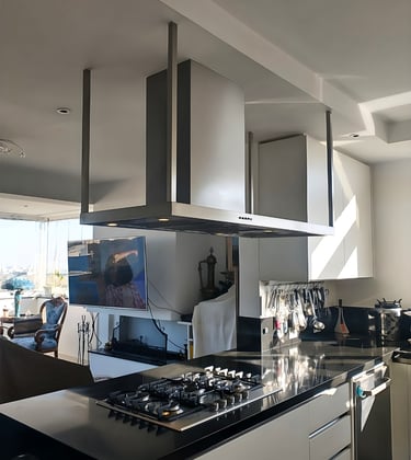Modern kitchen featuring a stainless steel island range hood over a black granite countertop with a gas stove.