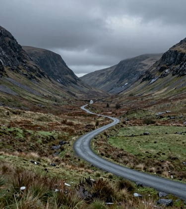 A wide, atmospheric landscape photo of a winding road through a glen in the Northern European / Scottish Highlands. Moody deep slate grey mountains tower over muted sage green fields. The lighting is cinematic, highlighting the rugged textures of the wild landscape.