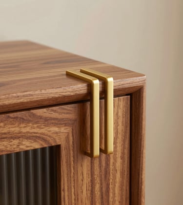 Close-up photography of bespoke, custom-made furniture in a South Asian / Indian home. A hand-finished wood surface meets matte gold hardware. The lighting emphasizes texture and fine detail. Background is a soft, out-of-focus ivory wall, conveying luxury in every corner.
