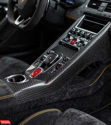 Detail shot of a Lamborghini's carbon fiber interior and yellow stitching. High contrast lighting highlighting texture and craftmanship. Sophisticated, dark atmosphere reflecting #1A1A1A and #5C5046.