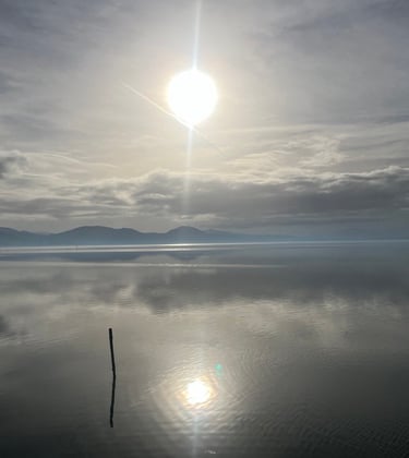 lago trasimeno with a bright sun shining through the clouds