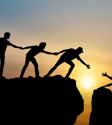Silhouettes helping other climb a mountain, symbolizing community and addiction recovery support