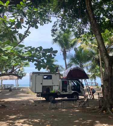 RV parked up against blue skies on the carribean coast at camping babsita in costa rica