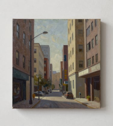 Detailed photograph of an urban-themed oil painting with sharp geometric lines and muted earth tones, displayed in a minimalist North American / US studio.