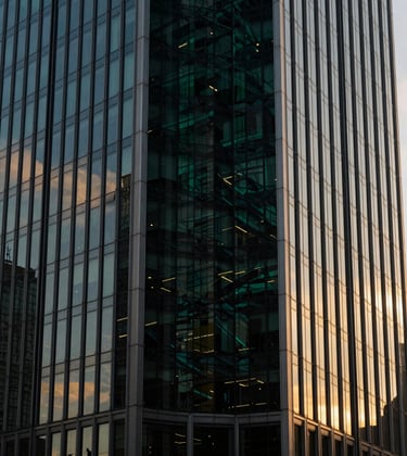 Abstract shot of a modern financial skyscraper in a Western market, with dark glass reflecting a deep green and gold sunset.