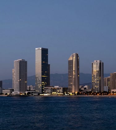 A panoramic photography shot of the Netanya, Israel coastline at dusk. Modern, illuminated luxury residential towers stand prominently against a deep navy sea and sky. The composition is clean and minimalist, focusing on architectural elegance and the prestige of the location.