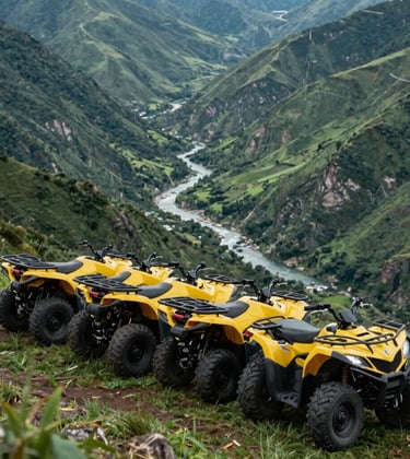 A line of four modern yellow quad bikes parked on a grassy mountain ridge overlooking a deep green valley with a river snaking through it.