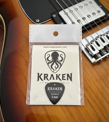 Kraken black guitar picks 2mm standard in packaging on a sunburst electric guitar body.