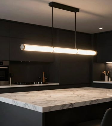A dramatic shot of a designer lighting fixture hanging over a polished white marble countertop in a luxury Los Angeles kitchen. The lighting creates a warm glow against the matte black surroundings, emphasizing a high-end design studio aesthetic.
