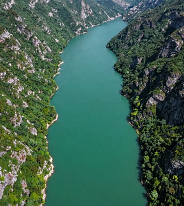 A cinematic aerial view of the turquoise waters of Uzungol lake nestled between steep, emerald green cliffs in the Trabzon region. The composition is clean and refreshing, emphasizing the natural beauty of the Eastern European / Turkish wilderness.