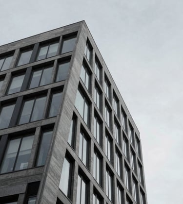 A minimalist architectural detail of a luxury financial building in Western Europe. Sharp geometric lines against a pale grey sky. The composition is clean and understated, emphasizing trustworthiness and modern elegance.