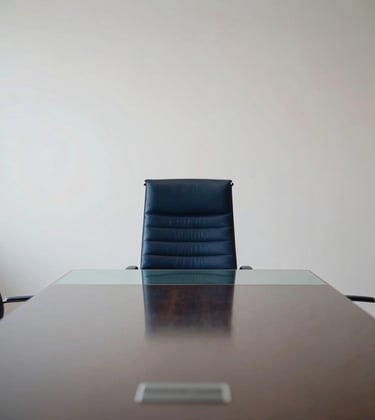 A wide shot of a minimalist, high-end meeting room in Luxembourg. A single navy leather chair sits at a glass desk. The composition is clean, centered, and reflects sophisticated professionalism.
