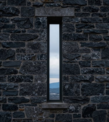 Detailed architectural photography of a singular, narrow vertical slit window in a dark stone wall, revealing a glimpse of a cold, high-altitude horizon. The mood is one of focused observation and control. North American / International Business context.