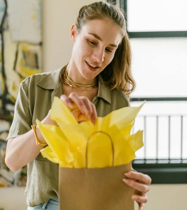 Mujer sonriente cerrando una bolsa de regalo de papel marrón