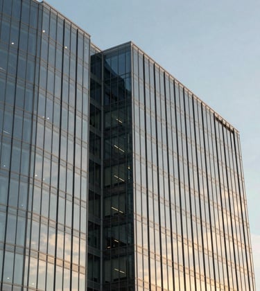 Clean architectural photograph of a sleek North American corporate office building with glass facades reflecting a pale blue sky and gold sunset tones.