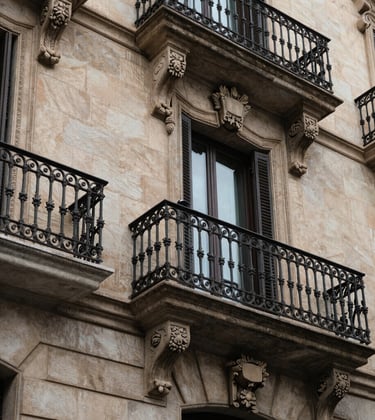 A close-up shot of architectural details in Barcelona, showing classic stone carvings and wrought iron balcony work in a luxury district.