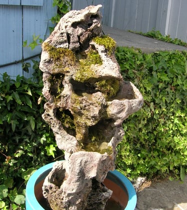 3.5-foot tall handmade stone column by Phil Mikkelson, moss-covered and designed as an outdoor water