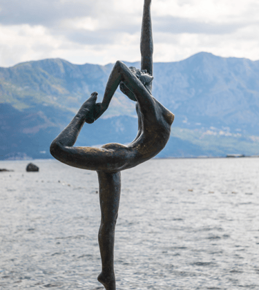 a statue of a woman doing yoga on a rock