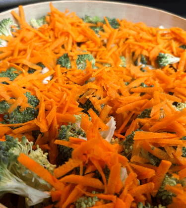 Broccoli florets and sliced carrots in a bamboo steamer ready to cook.