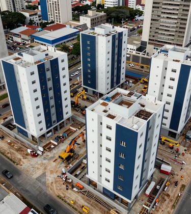 An aerial view of an active construction site for a modern residential complex in a South American / Brazilian city. The image highlights heavy machinery and structural foundations, featuring clean pearl white and deep navy blue elements. The vibe is of solid execution and industrial precision.
