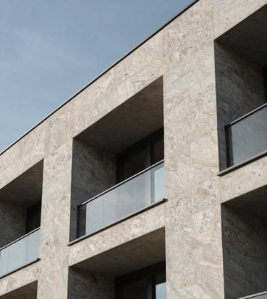 Modern stone facade of a high-end property in Cologny, Switzerland. Architectural detail focusing on luxury materials and minimalist design under a clear sky.