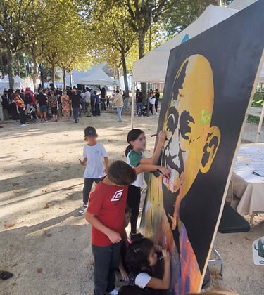 Children painting a large street art portrait of Mahatma Gandhi at an outdoor community festival.