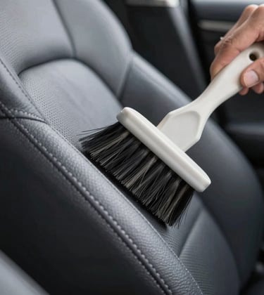Detailed shot of a professional detailing brush cleaning the stitching of a leather car seat. The lighting is precise, emphasizing textures. Colors reflect #A6A6A8 and #E8E9F3 palette.