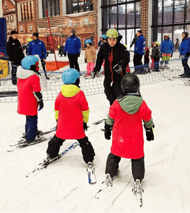grupo de niños y adultos en la nieve esquiando