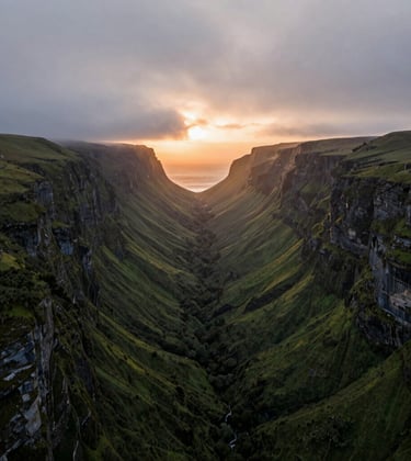 Cinematic drone photography of a lush Global / International coastal valley at dawn. Soft mist grey clouds hanging over green cliffs with deep amber sunset orange light peaking through.