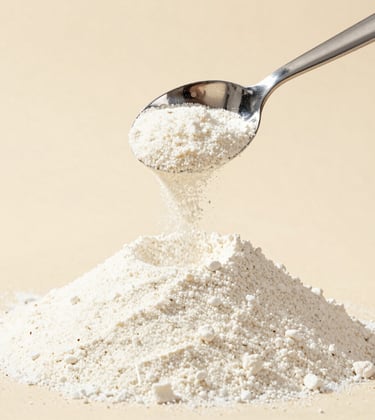 High-quality Guar Gum powder being carefully measured with a polished silver scoop. Clean, bright studio lighting against a soft beige background.