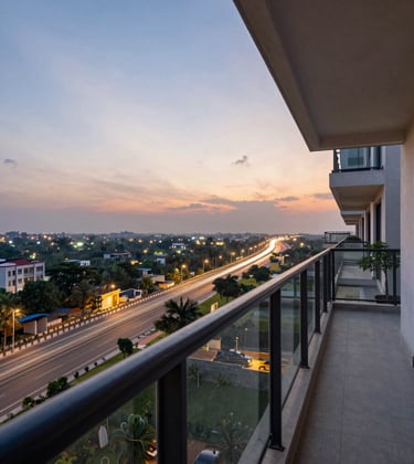 An expansive balcony of a high-end apartment overlooking the Greater Noida Expressway during sunset. The view shows distant architectural lights and lush greenery. South Asian / Indian modern residential development setting.