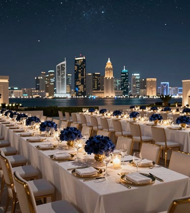 A wide shot of an elegant gala dinner under the stars at a luxury resort in Muscat. Long tables with white linens, gold accents, and deep navy floral arrangements. The city skyline glows in the background, Middle Eastern / Gulf evening vibe.
