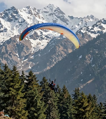A majestic shot of the Solang Valley in Manali, South Asian / Indian travelers enjoying a high-end paragliding experience with snow-capped mountains and sage green pine forests.