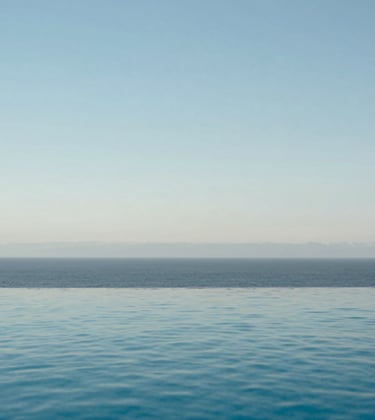 A serene infinity pool reflecting a soft light blue sky, part of a high-end coastal estate in North America, clean and minimalist design.