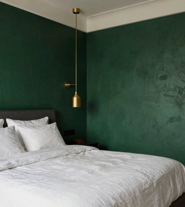 A high-end master bedroom featuring soft white linen bedding, royal dark green textured walls, and metallic gold pendant lights hanging from the ceiling.