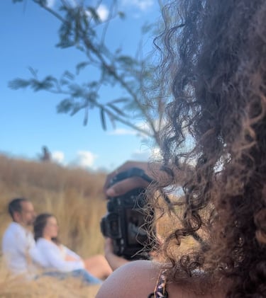 a woman taking a picture of a man in a field