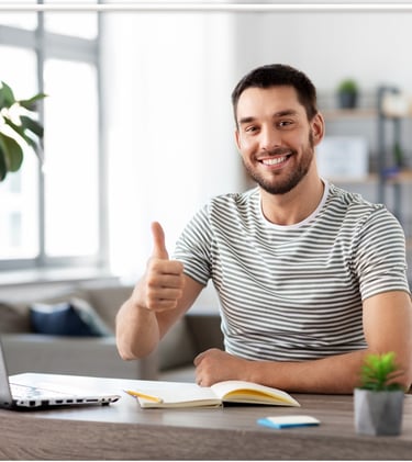 a man sitting at a desk with a laptop and a notebook