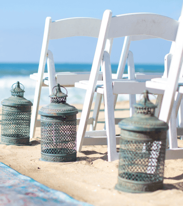 rustic blue metal lantern next to white wedding chair on beach