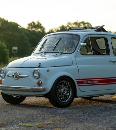 A photo of a blue grey 1974 Fiat 595 SS Abarth in a wooded setting at dusk.