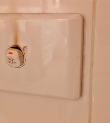 Burned electrical wall switch labeled hot plate showing brown scorch marks from overheating.