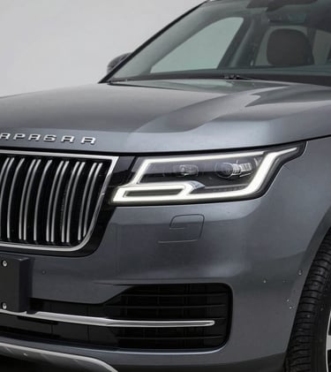 A close-up photograph of a premium luxury SUV grill and headlights, featuring a sleek charcoal grey finish, captured in a clean North American / US studio setting with soft lighting.